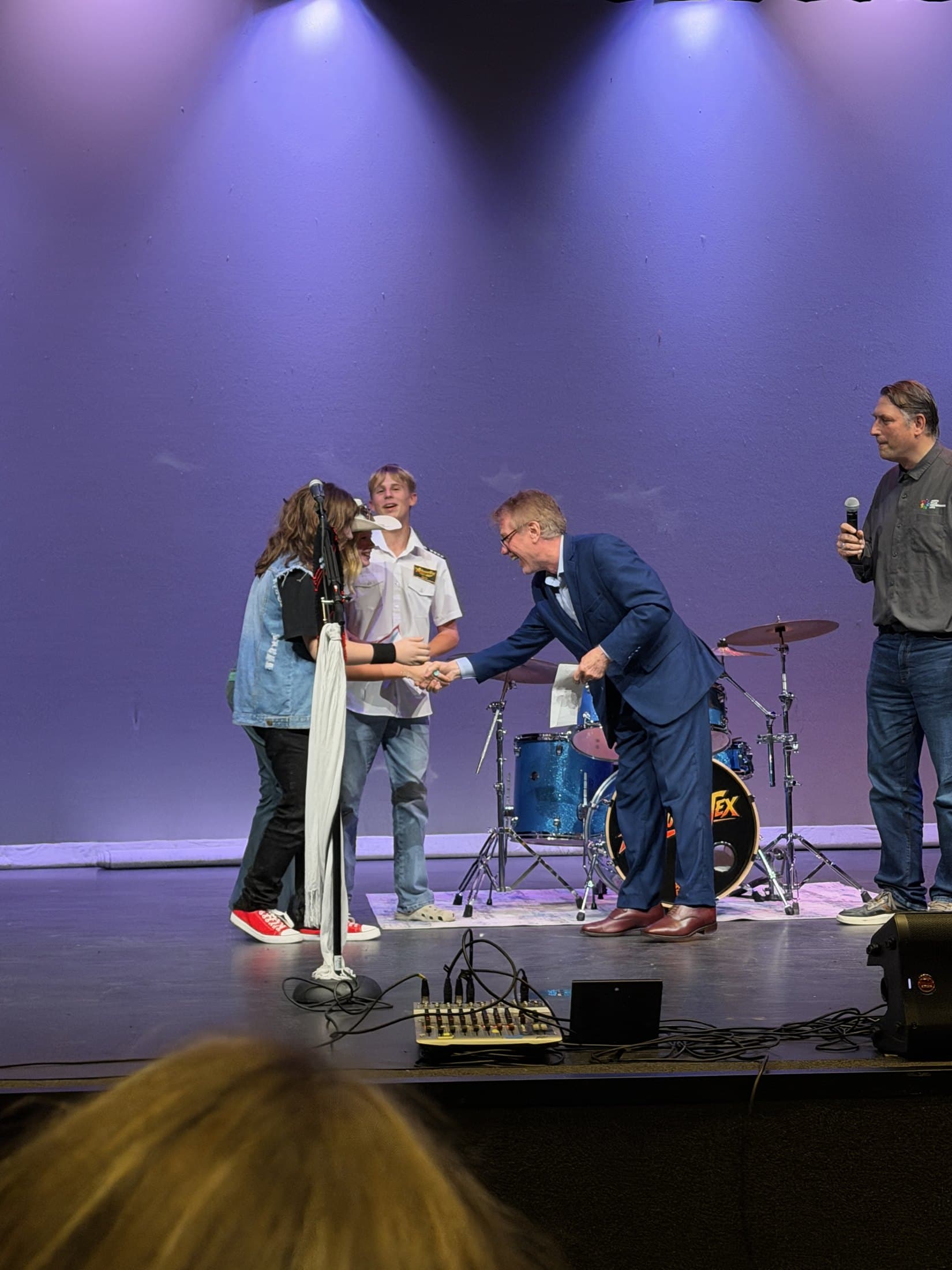 Jaxton Weatherly shakes hands with North Texas Performing Arts CEO Darrell Rodenbaugh as Airbourne Tex accepts first place in the youth division of North Texas Got Talent on Sept. 13, 2026, with bandmates Maryanne Hilton and Lucas Rehl. Photo: Airbourne Tex Team