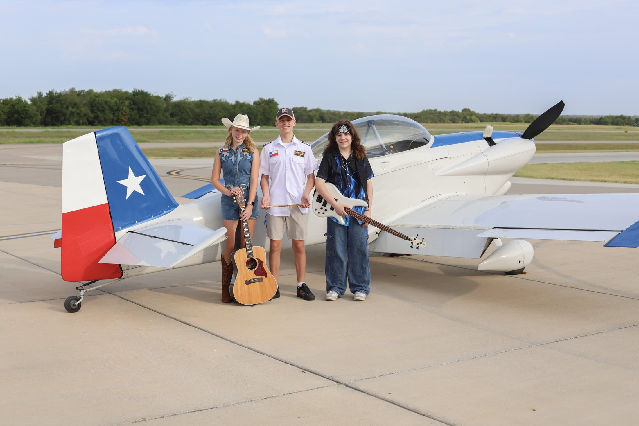Airbourne Tex with a Texas-flag-tailed plane at an Airplanes & Coffee fly-in in August 2026. From left: Maryanne Hilton, Lucas Rehl and Jaxton Weatherly. Photo: Jacey Rae Photography
